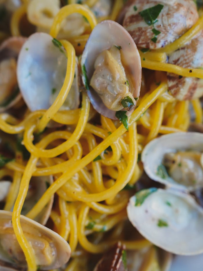 Close-up of appetizing clam pasta dish with parsley, capturing Italian culinary art.