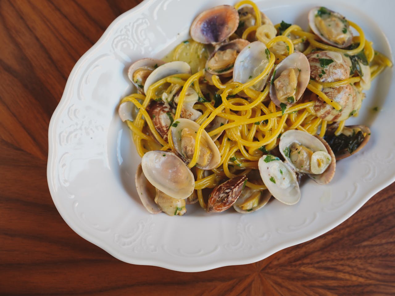 A savory Italian pasta dish with fresh clams served on a decorative white plate, perfect for seafood lovers.
